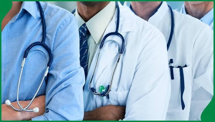 Doctors in white coats with stethoscopes standing with arms folded